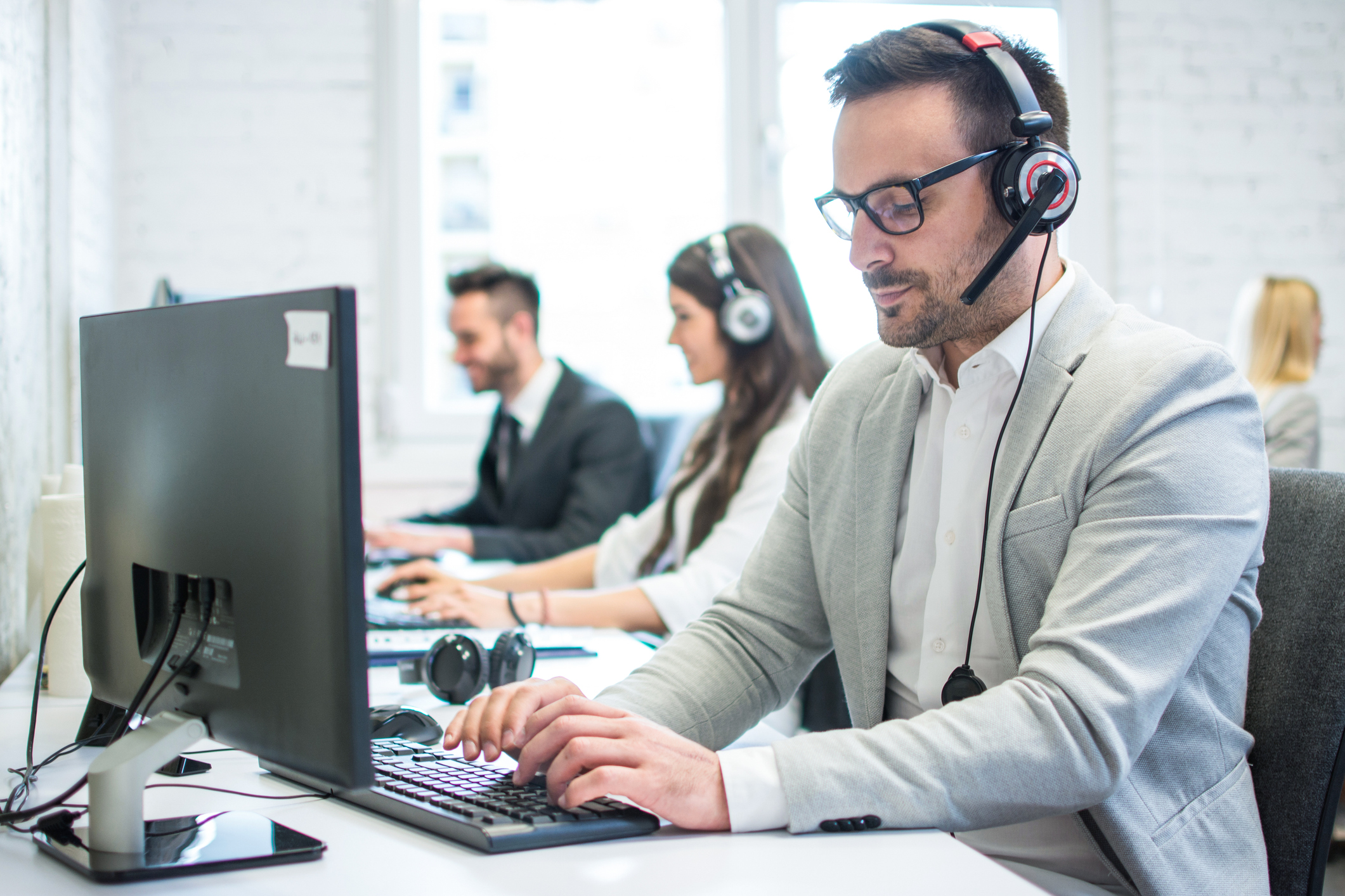 Concentrated male technical support operator working on computer in call centre.